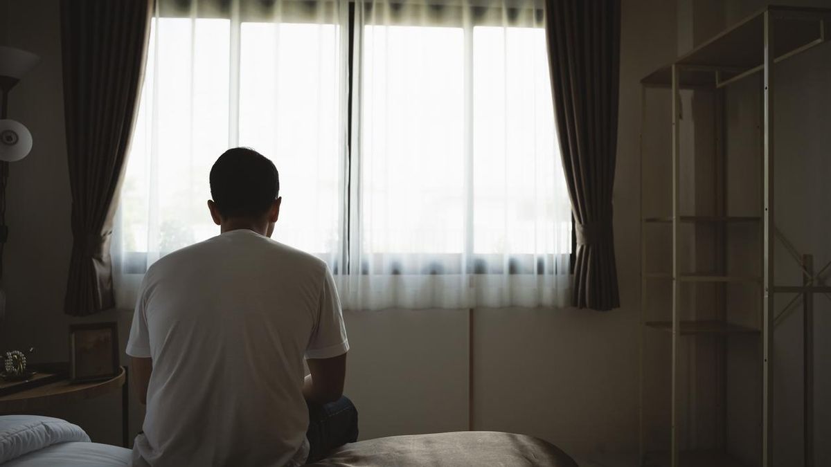 Un hombre sentado al borde de la cama.