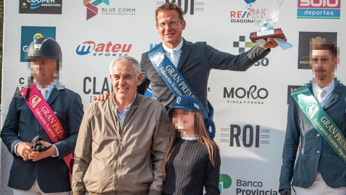 Augusto Fraschina, reconocido jinete e instructor de equitación, levanta un trofeo en una premiación, acompañado por el actual presidente de la Federación Ecuestre Argentina (FEA), Marcelo Brandolino.