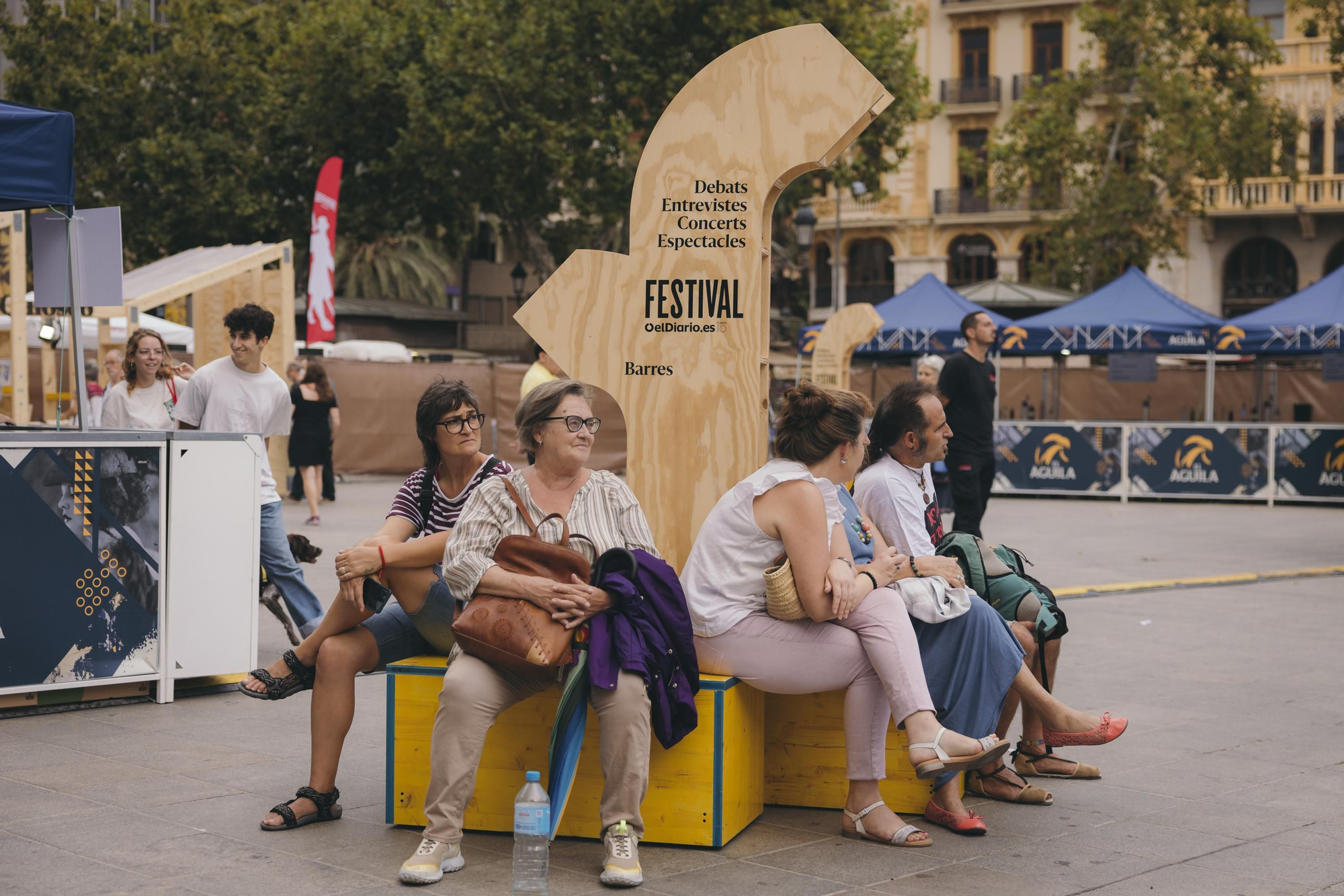 Un grupo de personas se reúnen en los bancos con señalización diseñados especialmente para el Festival de elDiario.es