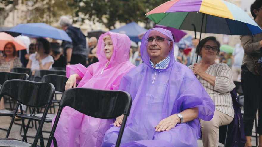 Dos lectores de elDiario.es se cubren ante la lluvia intermitente de la jornada del jueves